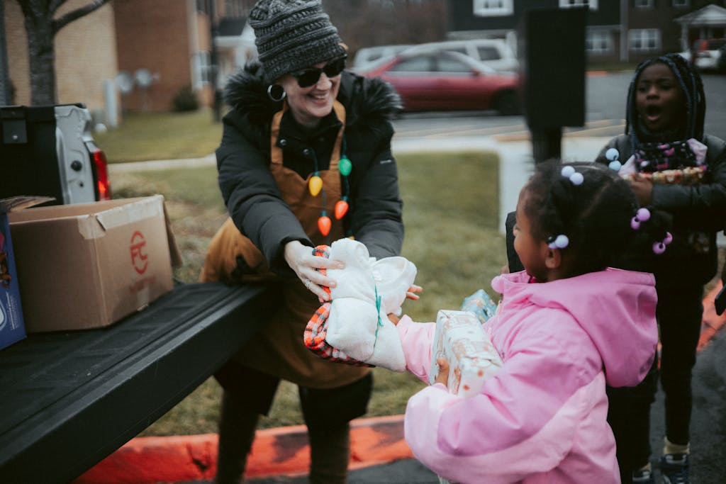 Volunteer exchanging holiday gifts with children, spreading festive cheer in a community setting.